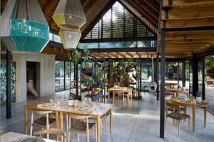 a restaurant with wooden tables and chairs and windows at Lion Sands River Lodge in Sabi Sand Game Reserve