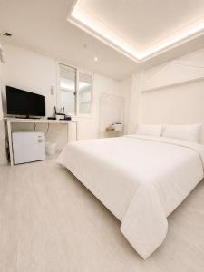 a white bedroom with a large white bed and a tv at Olli Haus in Seoul +41 photos