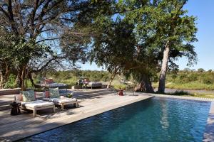 a swimming pool with chairs and a table next to a swimming pool at Lion Sands River Lodge in Sabi Sand Game Reserve