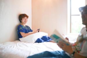 two women sitting on a bed reading books at Y Pub & Hostel Tottori in Tottori +45 photos