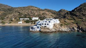 a group of white buildings on a island in the water at Psili Ammos in Mylopotas