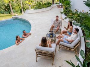 a group of people sitting around a pool at Villa Kahuna Sotogrande in Sotogrande