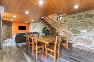 a dining room with a wooden table and a stone wall at Casa De Pedra D'alborinhas in Arões