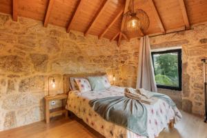 a bedroom with a bed in a stone wall at Casa De Pedra D'alborinhas in Arões +23 photos