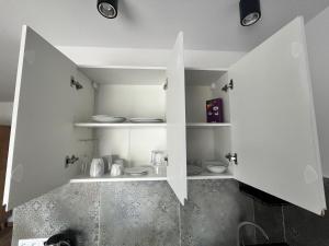 a kitchen with white walls and white shelves at Diament Apartamenty in Rowy +84 photos