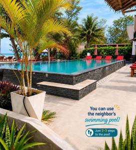 a swimming pool at a resort with chairs and a palm tree at All At Sea Beach Resort in Ban Tai