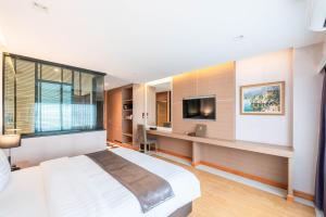 a bedroom with a bed and a desk and a tv at โฮเทลมุก in Mukdahan