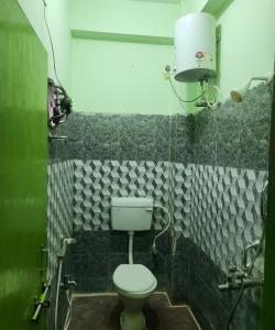 a bathroom with a toilet and a green tiled wall at SWAYAMSIDDHA continental in Kendrāparha +13 photos