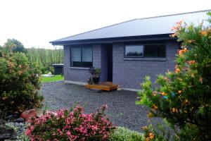 a house with a garden with flowers in front of it at Bordeaux Retreat in Te Kauwhata