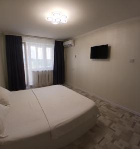 a bedroom with a white bed and a television at Циолковского с кодовым замком in Oral