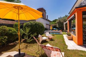 a yellow umbrella sitting in a yard next to chairs at La Maison Pop avec Piscine Privée in Romans-sur-Isère