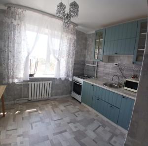 a kitchen with blue cabinets and a sink and a window at Циолковского с кодовым замком in Oral