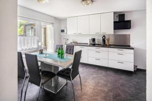 a kitchen with white cabinets and a table and chairs at Ferienhaus Maag, 102qm in Attendorn