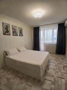 a bedroom with a white bed and a window at Циолковского с кодовым замком in Oral