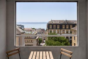 a window with two benches and a view of a city at Neuchâtel City Hôtel - Self Check-In in Neuchâtel