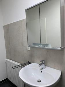 a bathroom with a white sink and a mirror at H4 Erdgeschoss in Nellingen