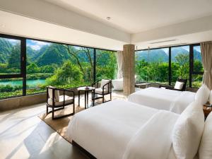 a bedroom with two beds and a large window at The Dragons Rest Sanctuary-Yulong River Branch - Infinity Pool & Cafe - English Speaking Service - Free MTB Rental & Tailor-Made Tour Service in Yangshuo +80 photos