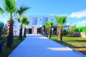 a pathway with palm trees in front of a building at Vila Bashkim in Ksamil