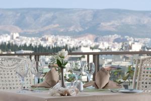 a table with glasses and flowers on a table with a view at The Athenian Callirhoe in Athens