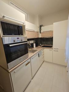 a kitchen with white cabinets and a stove top oven at Borisz Apartman in Makó