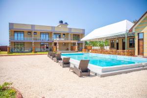 a swimming pool with lounge chairs in front of a building at Tulivu Resort in Kituoni