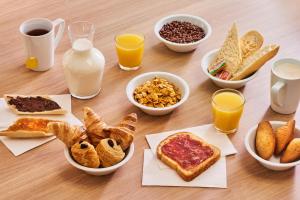 a table topped with bowls of breakfast foods and glasses of milk at Premiere Classe Marne la Vallée - Torcy in Torcy