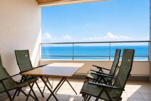 a table and chairs on a balcony with a view of the ocean at Villa JacoO 2 in Sanuki