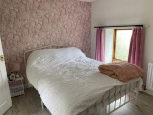 a bedroom with a bed with pink walls and a window at The Cottage in Middlesbrough
