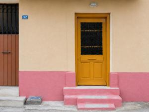 a yellow door on the side of a pink building at Elegant Studio in Chios near the Beach and Port in Chios