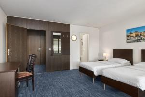 a hotel room with two beds and a desk at Neuchâtel City Hôtel - Self Check-In in Neuchâtel