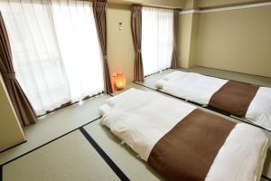 two beds in a room with two windows at Wallaby House in Kawaguchi