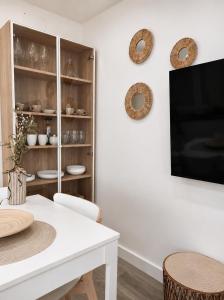 a dining room with a white table and a tv at Sisargas Playa in Malpica