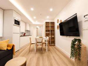 a living room with a table and a tv on a wall at Sisargas Playa in Malpica