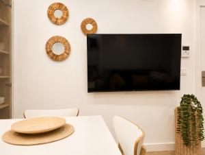a dining room with a white table and a flat screen tv at Sisargas Playa in Malpica