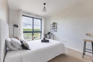 a white bedroom with a large bed with a window at 102 - L'Obsidienne - Wifi in Achères