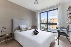 a bedroom with a white bed and a large window at 102 - L'Obsidienne - Wifi in Achères