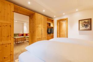 a bedroom with two beds and a living room at Hotel Aurora in Lech am Arlberg