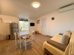 a living room with a table and a kitchen with a refrigerator at Apartments Vicelić in Lovište