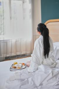 a woman sitting on a bed with a tray of food at Hotel Oktogon Haggenmacher by Continental Group in Budapest
