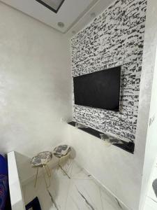 a living room with two stools and a tv on a brick wall at Martil in Martil