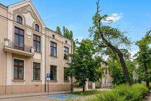 a building with a tree next to a street at Lumiere 28 Aparthotel in Łódź