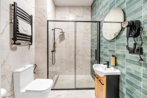 a bathroom with a shower and a toilet and a sink at Lumiere 28 Aparthotel in Łódź