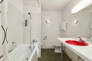 a bathroom with a red sink and a bath tub at Neuchâtel City Hôtel - Self Check-In in Neuchâtel +43 photos
