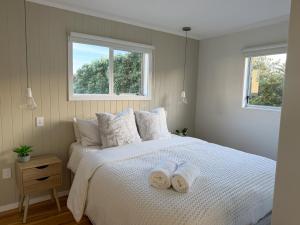 a bedroom with a white bed with towels on it at Waikanae Beach Abode in Waikanae