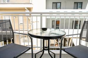 a glass table and two chairs on a balcony at Le Bel Appartement D'Antigoni in Alexandroupoli