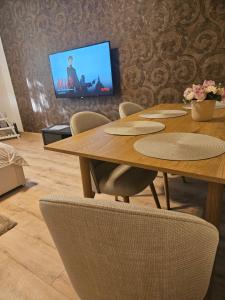 a table with chairs and a television in a room at Borisz Apartman in Makó