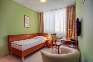 ein Schlafzimmer mit einem Bett, einem Schreibtisch und einem Stuhl in der Unterkunft Ensana Spa Smrdáky in Smrdáky