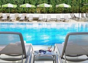 a pool with chairs and a table next to a swimming pool at Brown Jerusalem Hotel in Jerusalem