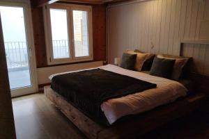 a large bed in a bedroom with two windows at 20 Min nach Interlaken in Frutigen