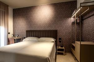 ein Schlafzimmer mit einem großen weißen Bett und einer Wand in der Unterkunft Hotel Costa Azzurra in Grado